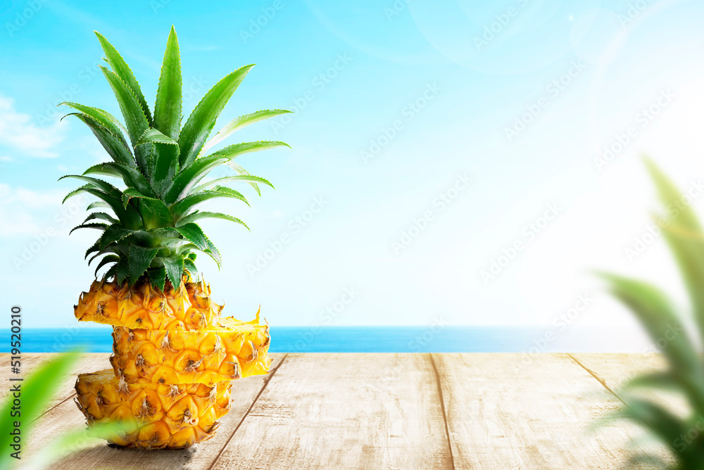 Obraz premium Slice of fresh pineapple on wooden table with ocean view