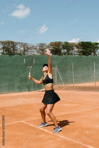 young sporty blonde girl dressed in black playing tennis on a sand court in the sun. High performance athlete © Beatriz