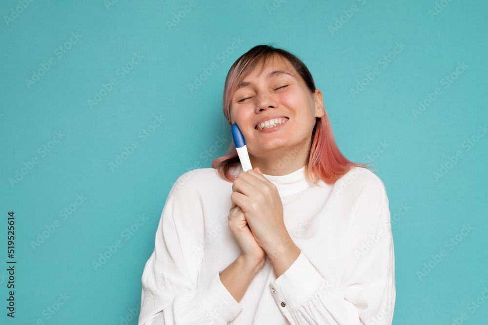 Happy young woman with pregnancy test on blue background Happy young woman with pregnancy test on blue background