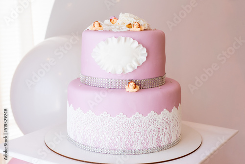 Two-tiered pink cake with a place for an inscription and little angels. Copy space