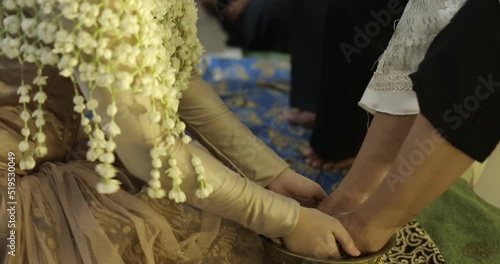 The bride washes her mother's feet. The term siraman  itself comes from the word flush which in Javanese means bathing. Siraman is done as a symbol of inner and outer cleansing. photo