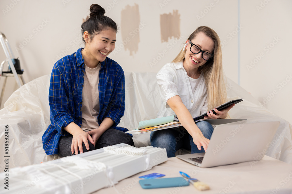 A young Asian beauty woman is happy with the design project of her new apartment prepared for her by a beautiful blonde woman who is an architect. The women get along perfectly with each other, they A young Asian beauty woman is happy with the design project of her new apartment prepared for her by a beautiful blonde woman who is an architect. The women get along perfectly with each other, they