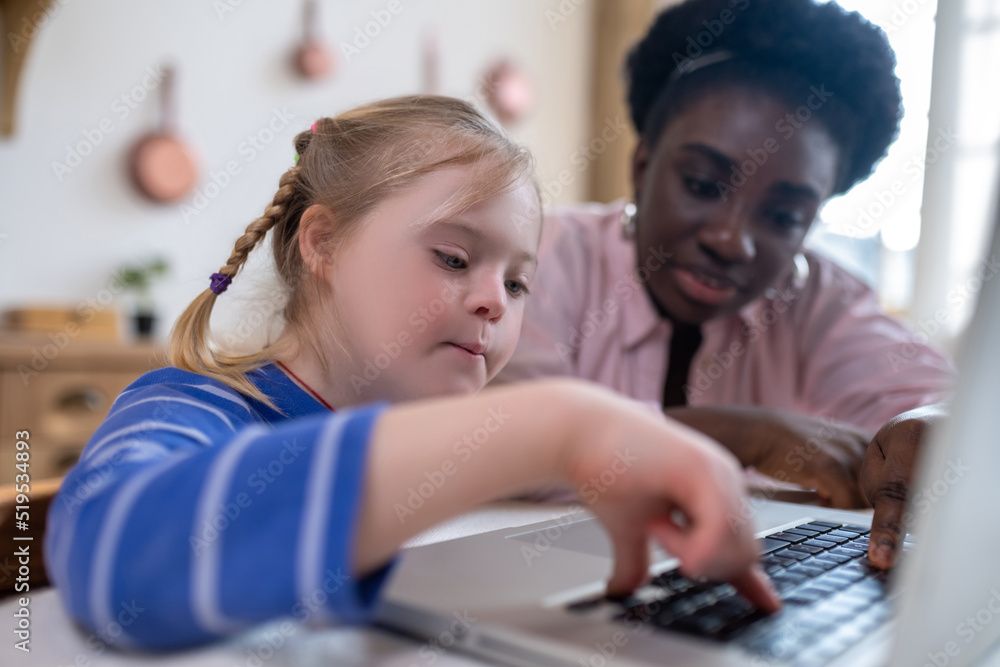 © zinkevych - A girl with down syndrome sitting at the laptop with her tutor © zinkevych - A girl with down syndrome sitting at the laptop with her tutor