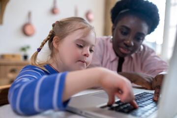 A girl with down syndrome sitting at the laptop with her tutor