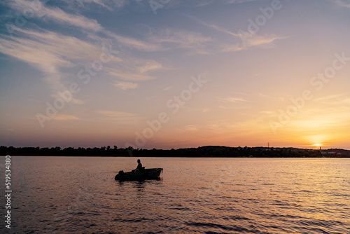 Fishing boat over beautiful sunset background.