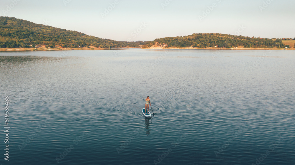 High angle view of woman paddling SUP board on lake.