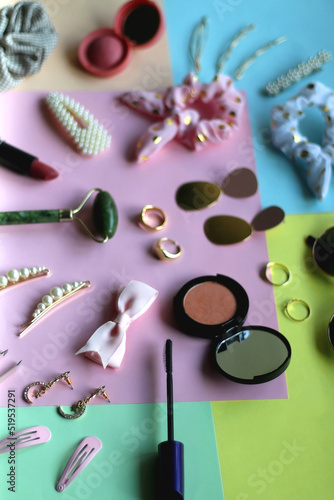 Various accessories, make up products and jewelry on various colorful pastel backgrounds. Selective focus.