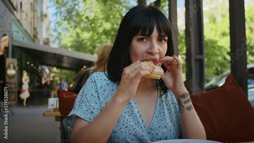 a happy woman enjoys delicious food in a street cafe, rejoices in this taste and smell.