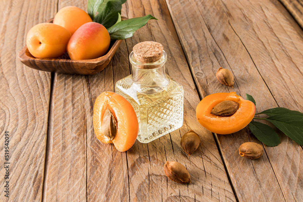 apricot oil in glass bottle on the background of ripe apricots and seeds. wooden background. the concept of rejuvenation, moisturizing the skin. apricot oil in glass bottle on the background of ripe apricots and seeds. wooden background. the concept of rejuvenation, moisturizing the skin.