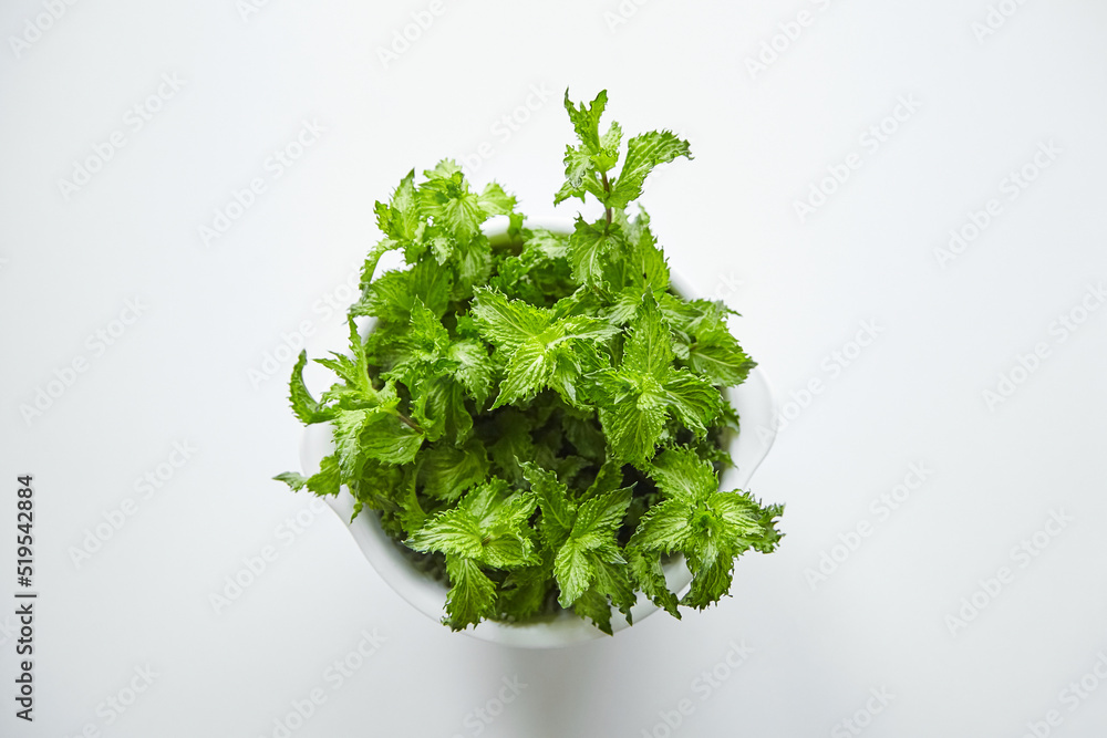 Obraz premium Fresh mint leaves in bowl, medicinal herb, top view