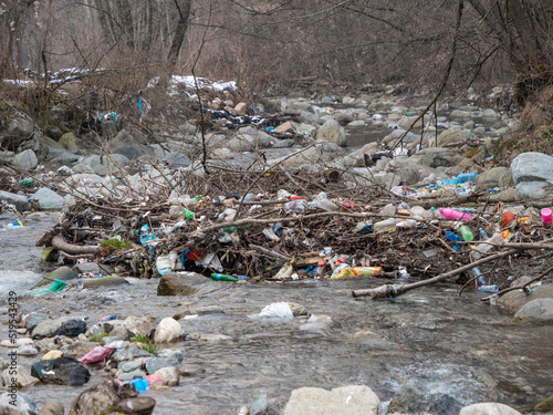 Flowing river and its banks littered with a pile of plastic garbage.
