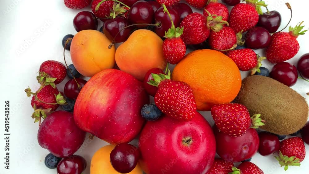 Different fruits and berries lie on a white background and rotate in a circle. High quality 4k footage Different fruits and berries lie on a white background and rotate in a circle. High quality 4k footage