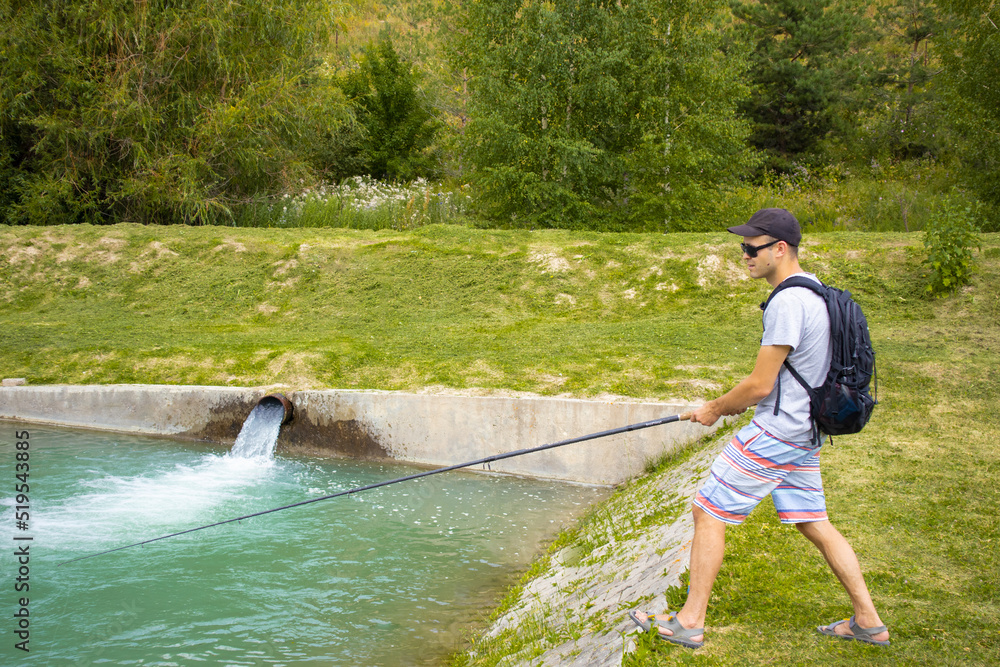 fishing on a trout farm. a guy is fishing on a trout farm fishing on a trout farm. a guy is fishing on a trout farm