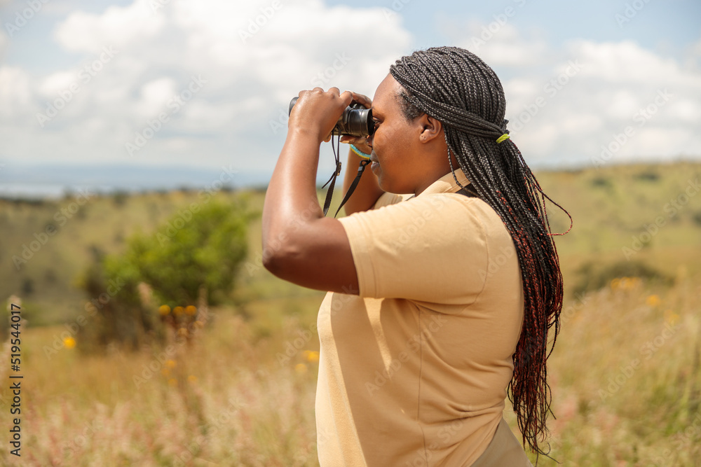 Side view of African American female guide looking for wildlife in Africa, copy space