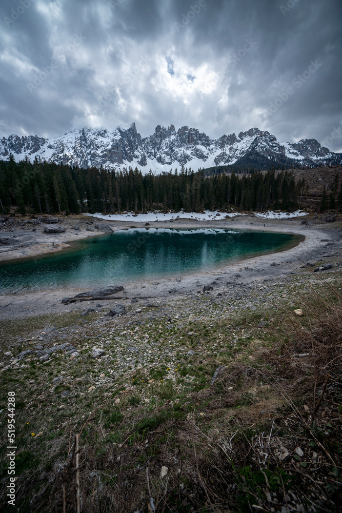Stormy clouds over Dolomites reflecting in water of Lake Carezza located in south Tirol