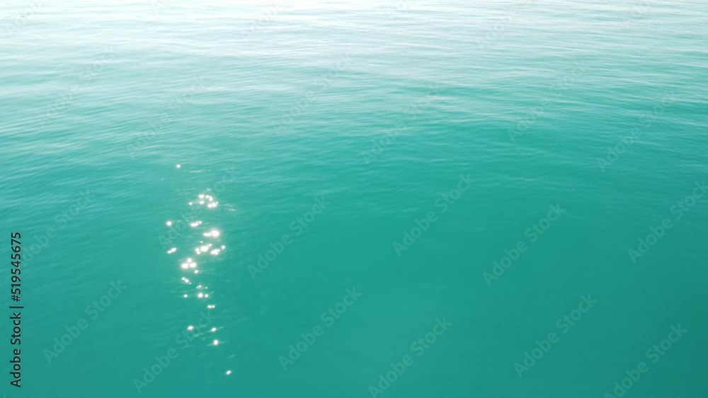 Abstract aerial sea summer ocean sunset nature background. Small waves on water surface in motion blur with golden bokeh lights from sun. Holiday, vacation and recreational concept. Slow motion Abstract aerial sea summer ocean sunset nature background. Small waves on water surface in motion blur with golden bokeh lights from sun. Holiday, vacation and recreational concept. Slow motion