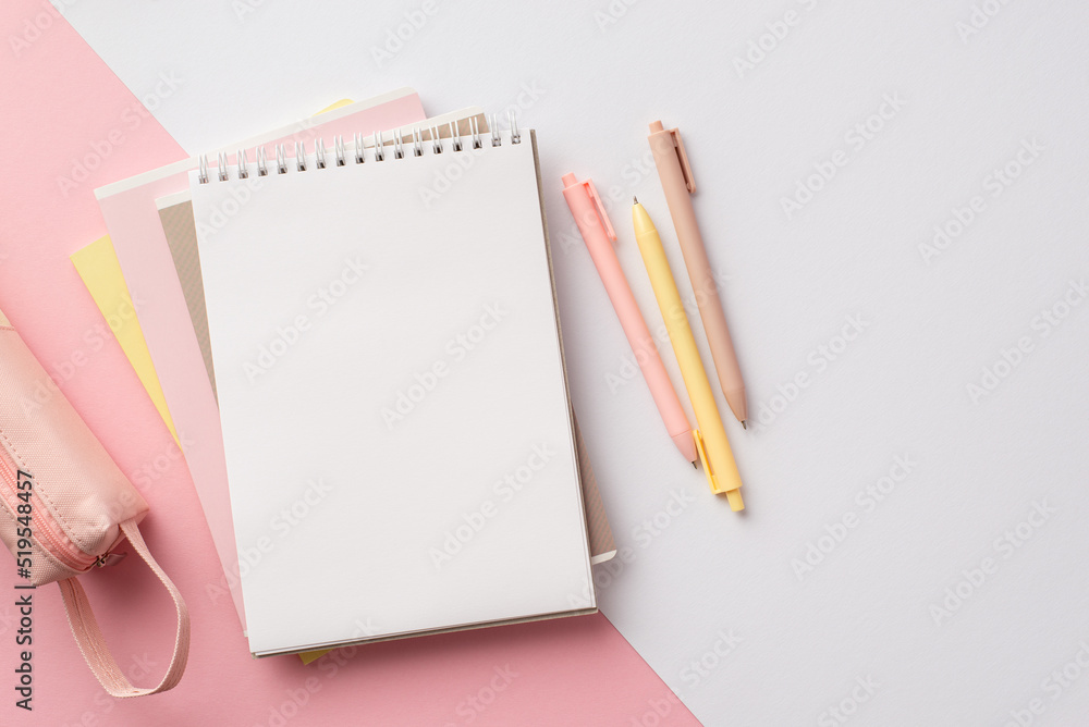 School supplies concept. Top view photo of pink and yellow stationery stack of planners pens and pencil-case on bicolor pink and white background with empty space School supplies concept. Top view photo of pink and yellow stationery stack of planners pens and pencil-case on bicolor pink and white background with empty space