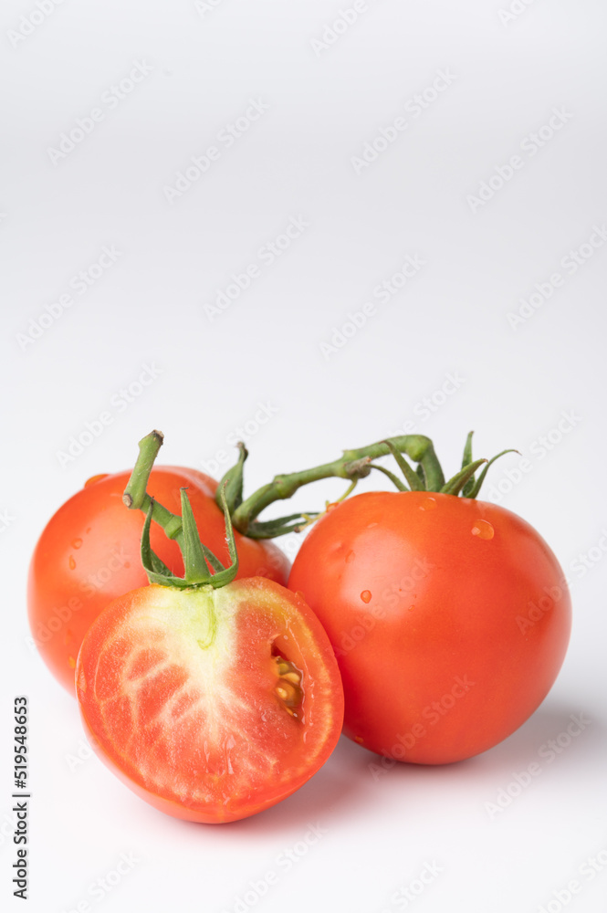 Fresh tomatoes on a green stem on white Fresh tomatoes on a green stem on white