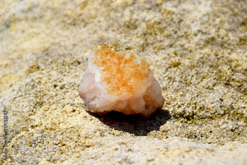 A beautiful druse citrine lies on a stone. Intergrowth of yellow crystals of semi-precious quartz in bright sunlight.