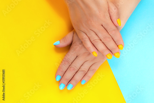Hands with a manicure on a yellow-blue background