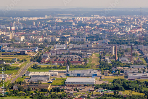 ariel panoramic view of city and skyscrapers with a huge factory with smoking chimneys in the background © hiv360