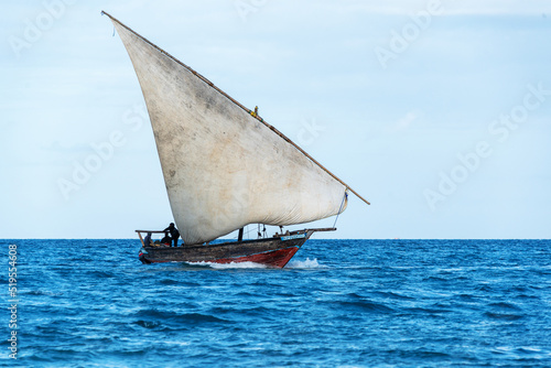 sailing dhow heading for harbour full sails and choppy ocean photo
