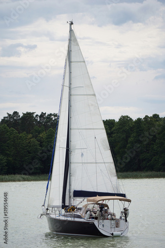 Fototapeta Naklejka Na Ścianę i Meble -  Sailboat swimming on a lake - back view