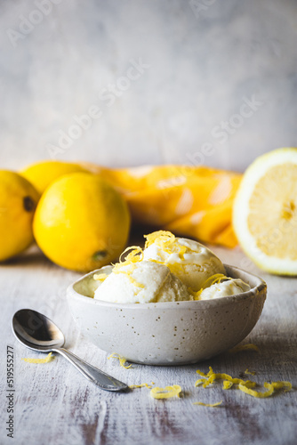 Photos cuenco con bolas de helado de limón sobre una mesa de madera blanca, con limones