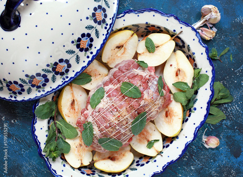 Pork roll with pears, mint leaves and spices in a ceramic baking dish. Selective focus.
