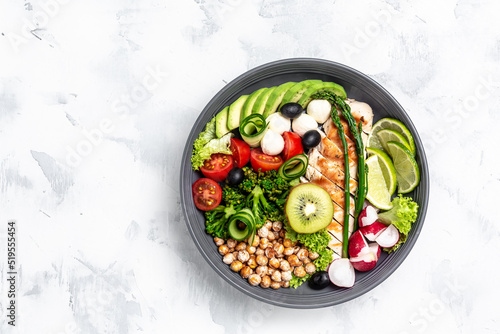 Buddha bowl dish with chicken fillet, avocado, asparagus, chickpeas, broccoli, radish, chicken, cucumber, tomatoes, olives, mozzarella. Detox and healthy superfoods concept, top view