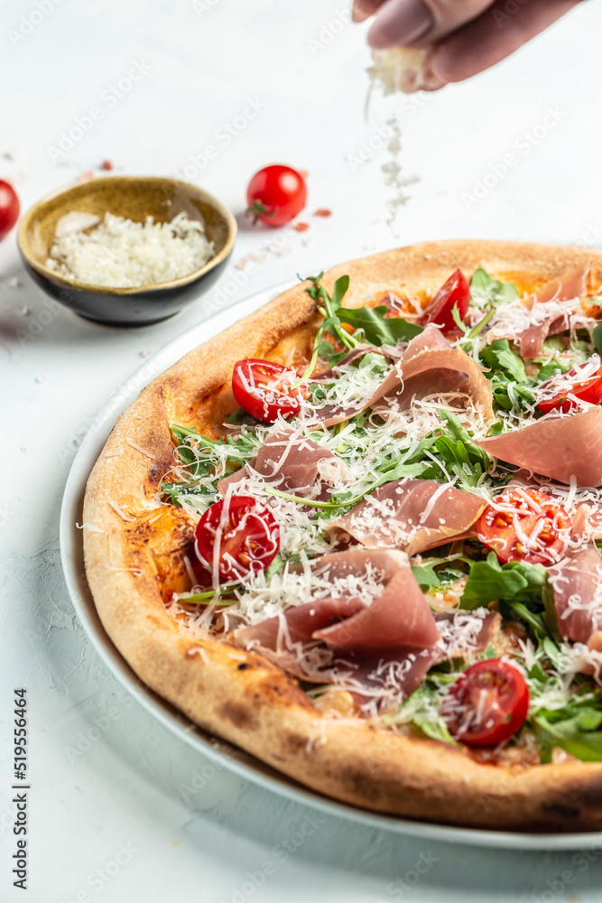 Appetizing italian pizza with cheese, prosciutto, arugula and parmesan. Baked pizza with salami, prosciutto red sauce and cheese. Top view