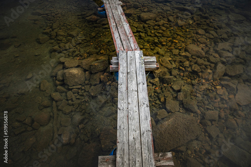 Beautiful small bridge of tree in a small lake with still water and reflection of the sky in surface