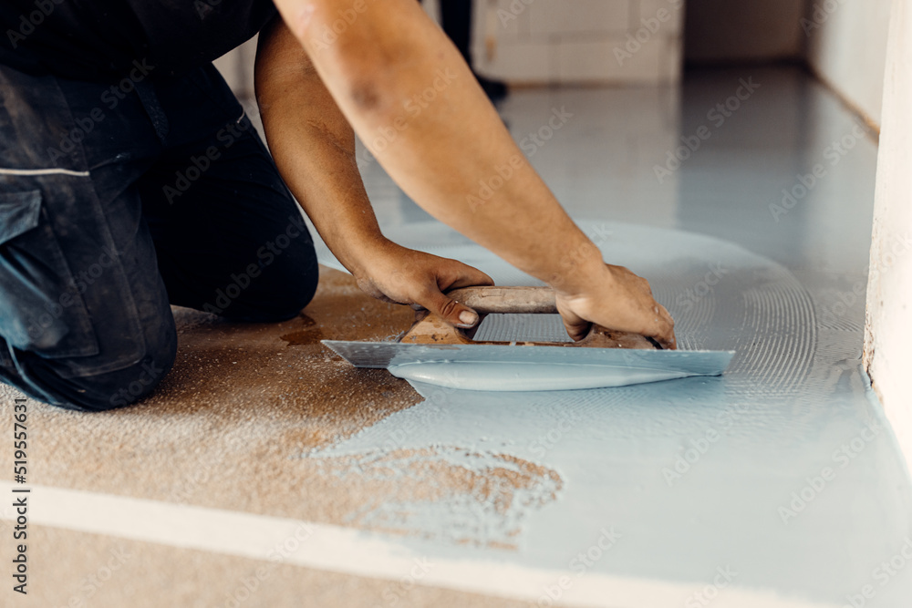 Construction worker apply grey epoxy resin in an industrial hall Construction worker apply grey epoxy resin in an industrial hall