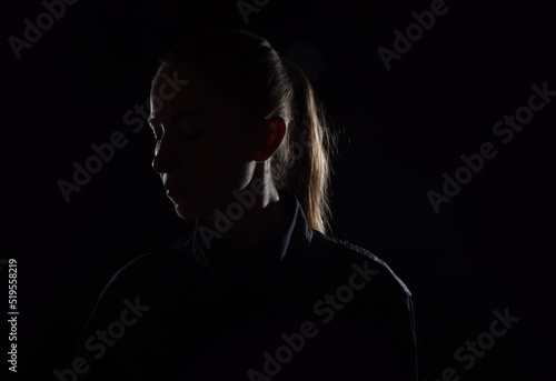 Female person silhouette in the shadow, back lit light photo