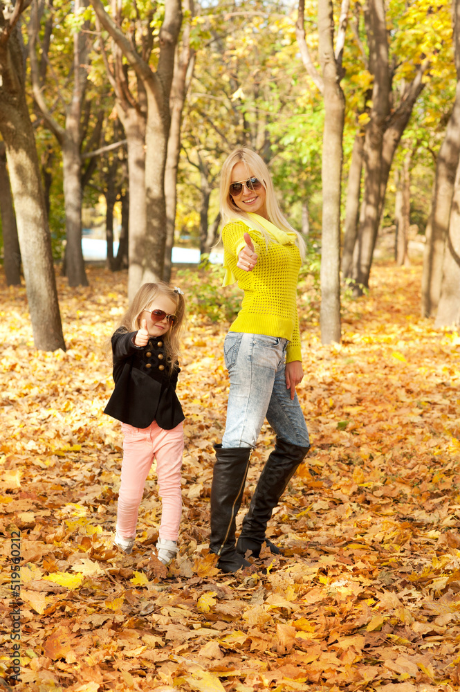 Young mother and little daughter playing fashion dressed in sunglasses in autumn park. Young mother and little daughter playing fashion dressed in sunglasses in autumn park.