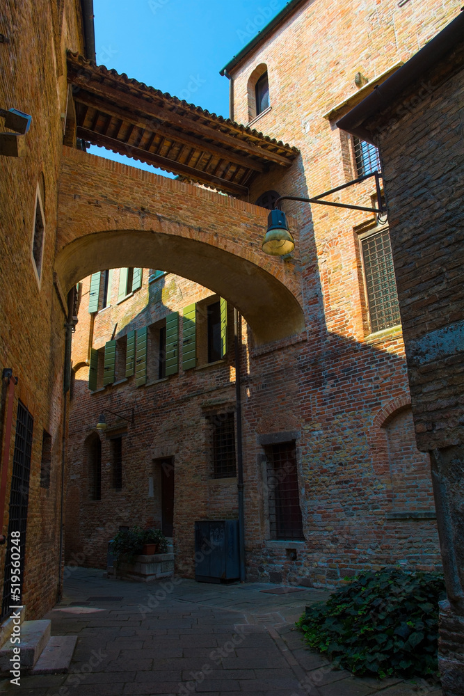 Two historic building in a narrow medieval street are connected by an overhead arch walkway, in the centre of Treviso, Veneto, north east Italy
