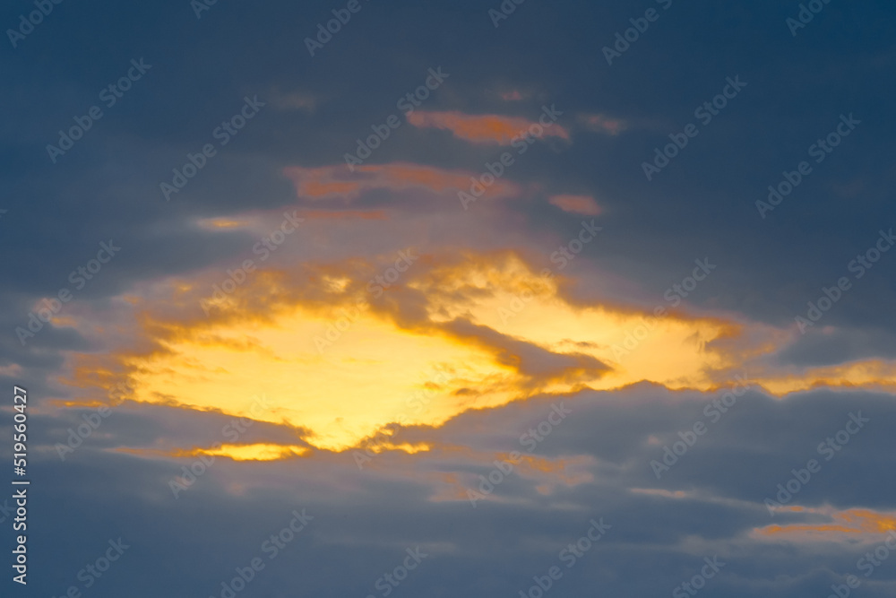 Light spot orange sunset through dark rain clouds storm beam light sky weather background