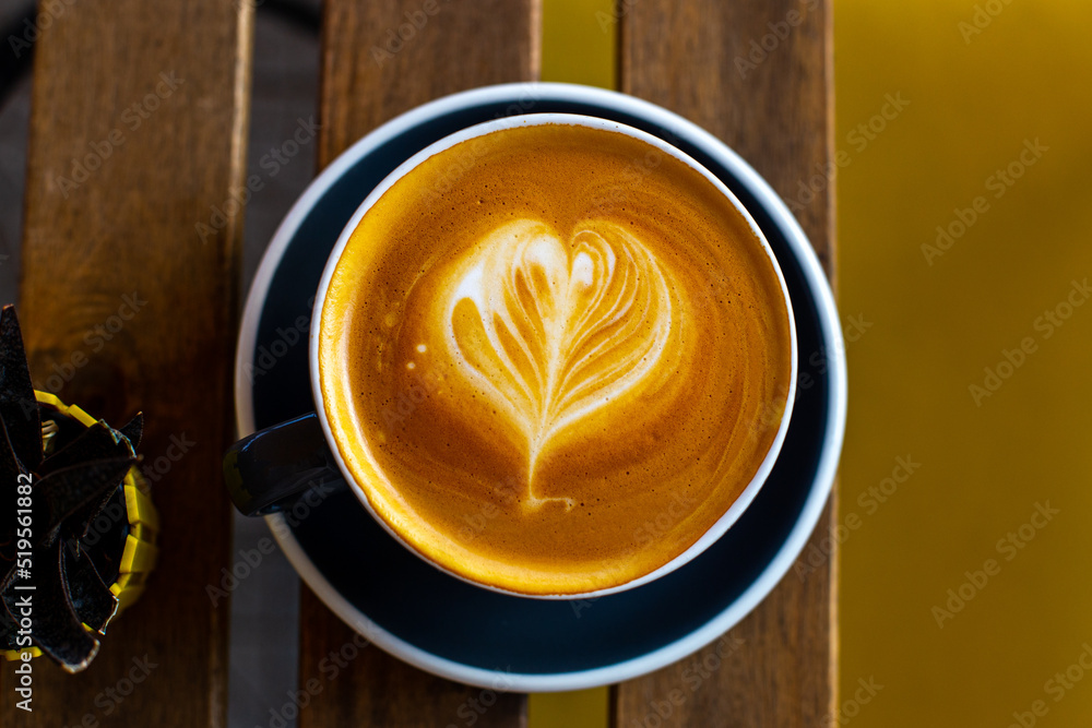 Black cup of cappuccino with latte art on wooden background. Black cup of cappuccino with latte art on wooden background.