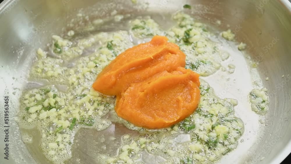Adding pumpkin puree in a frying pan.
Adding pumpkin puree in a frying pan.