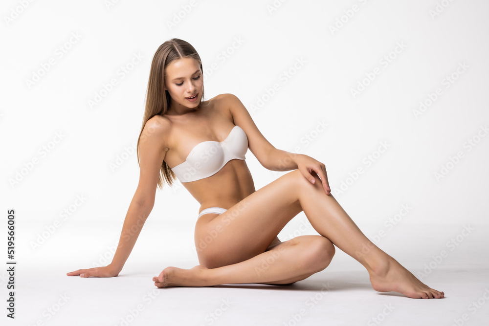 Young woman in cotton underwear sitting on white background