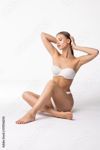 Young beautiful woman in white cotton underwear sitting on white background © F8  \ Suport Ukraine