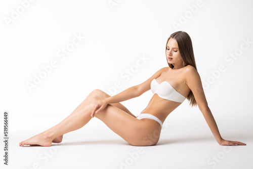 Young woman in cotton underwear sitting on white background