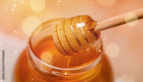 Golden honey flows from the stick and a jar. Aromatic nectar