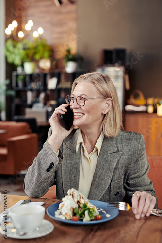Wallpaper Mural Successful mature businesswoman smiling while having conversation on mobile phone during her lunch at the restaurant Torontodigital.ca