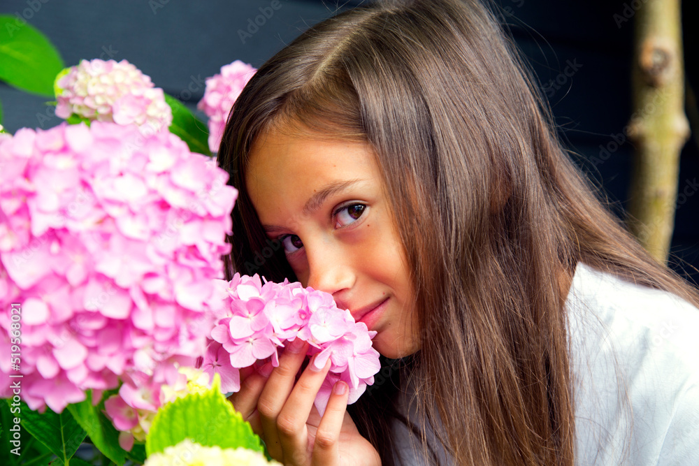 Portrait of a little beautiful girl with a bouquet of hydrangeas in her hands. Child girl smells hydrangea flowers. The concept of childhood, happiness, carelessness and nature. Portrait of a little beautiful girl with a bouquet of hydrangeas in her hands. Child girl smells hydrangea flowers. The concept of childhood, happiness, carelessness and nature.