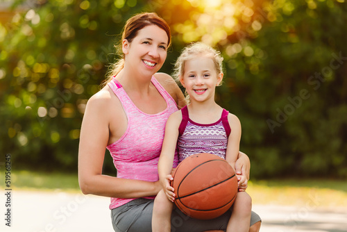 Happy mother and child daughter outside at basketball court.