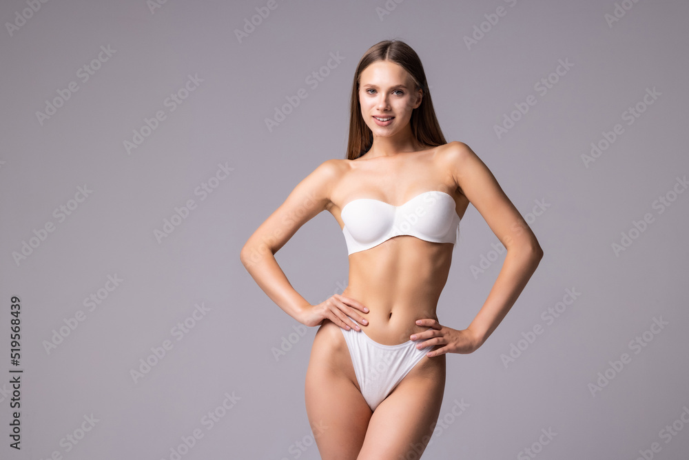 Smiling sporty woman in white underwear posing on studio background. Female beauty, sport, spa concept Smiling sporty woman in white underwear posing on studio background. Female beauty, sport, spa concept