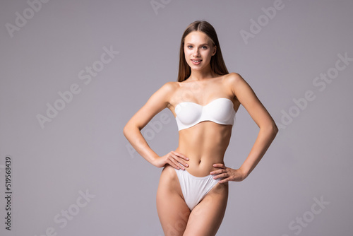 Smiling sporty woman in white underwear posing on studio background. Female beauty, sport, spa concept