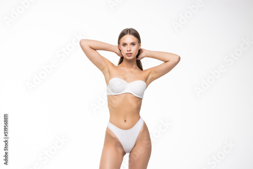 Slim tanned woman's body. Perfect body in white lingerie on white background. Beauty and body care concept