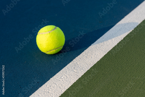 Yellow tennis ball at blue tennis court with white baseline and green out of bounds  © Thomas